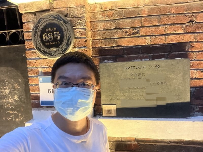 2022年，一位戴口罩的年轻男子在沙面大街68号的铭牌前自拍